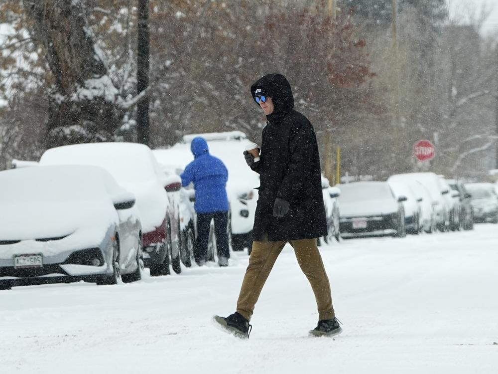 A pedestrian crosses First Avenue as a winter storm sweeps over the intermountain West, plunging temperatures into the single digits and bringing along a light snow in its wake Saturday, Jan. 18, 2025, in Denver.