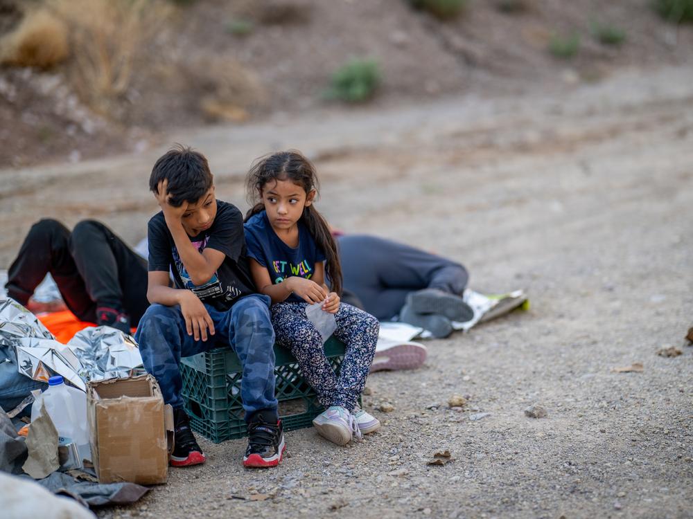 Children of the Rivera family look toward the sky while waiting to be apprehended by U.S. Customs and Border Protection officers after crossing over into the U.S. in June 2024 in Ruby, Ariz.