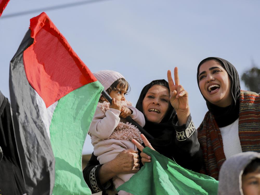 A Palestinian family holds up flags and celebrates their return to Rafah, Gaza Strip, on January 19, 2025.