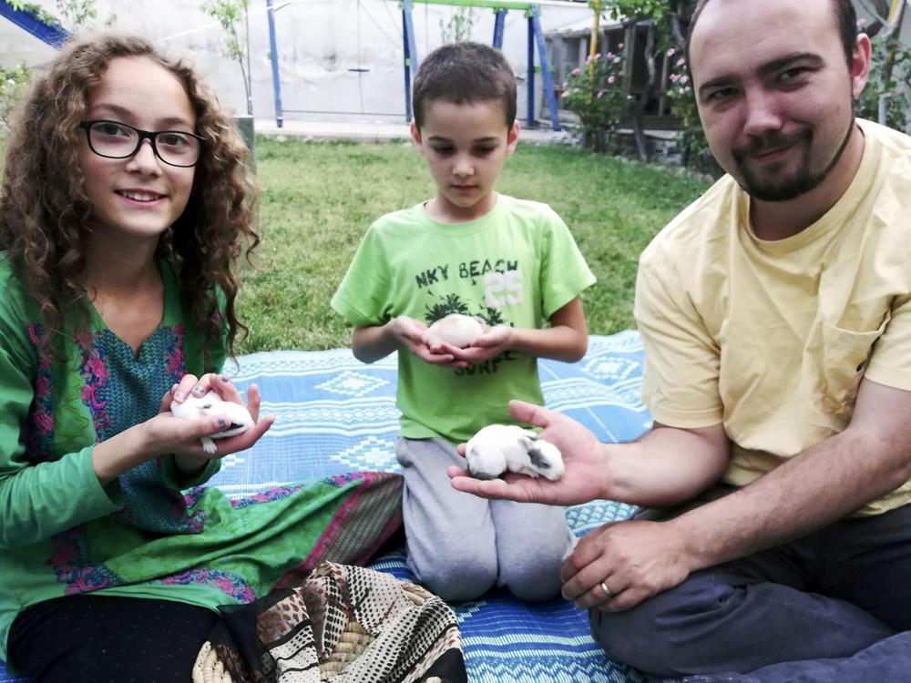 This family photo shows Ryan Corbett holding rabbits with his daughter Miriam and son Caleb in Kabul, Afghanistan in 2020.