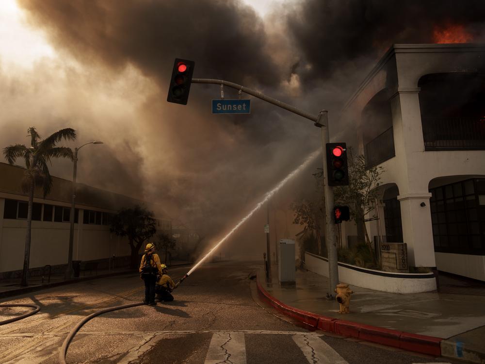Firefighters spray flames from the Palisades Fire in Los Angeles, California. The smoke and ash from the fires spread across the city — and now residents are worried about how to clean up safely.