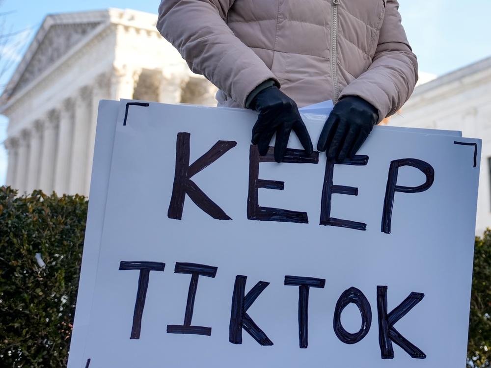 A content creator on TikTok holds a protest sign outside the Supreme Court building on Jan. 10 in Washington, D.C.