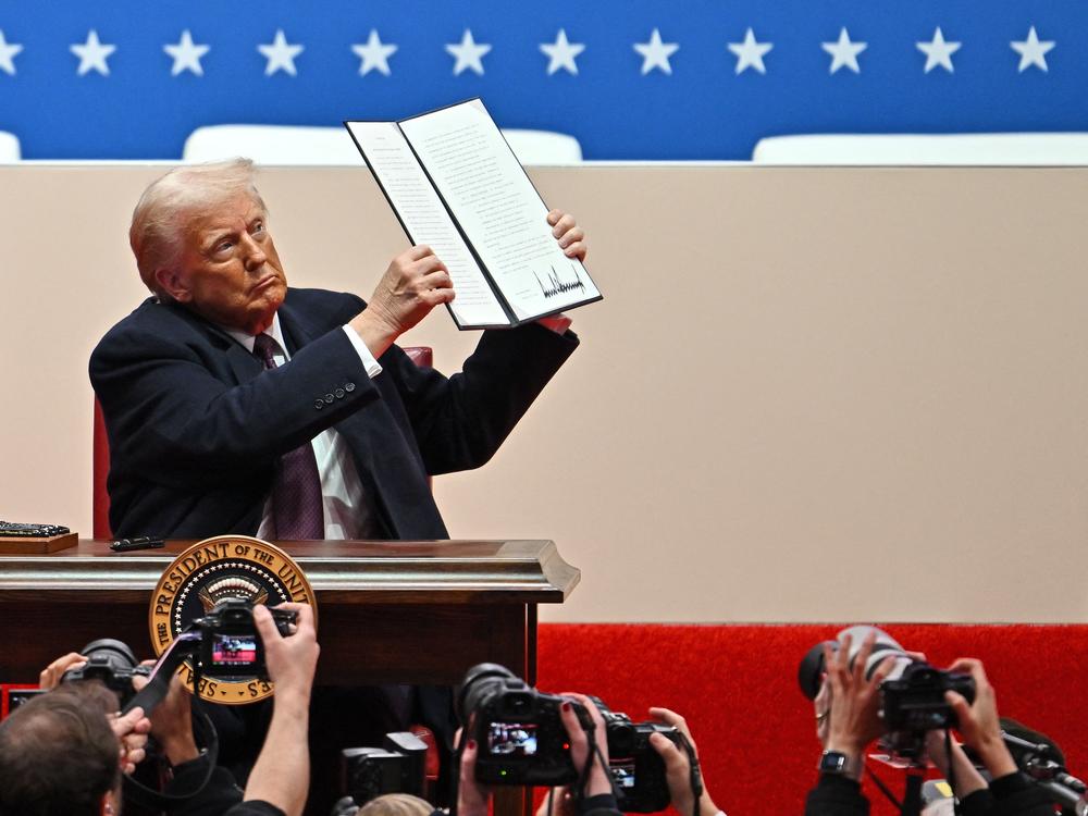Donald Trump signs executive orders during the inaugural parade inside Capital One Arena, in Washington, DC on Monday.