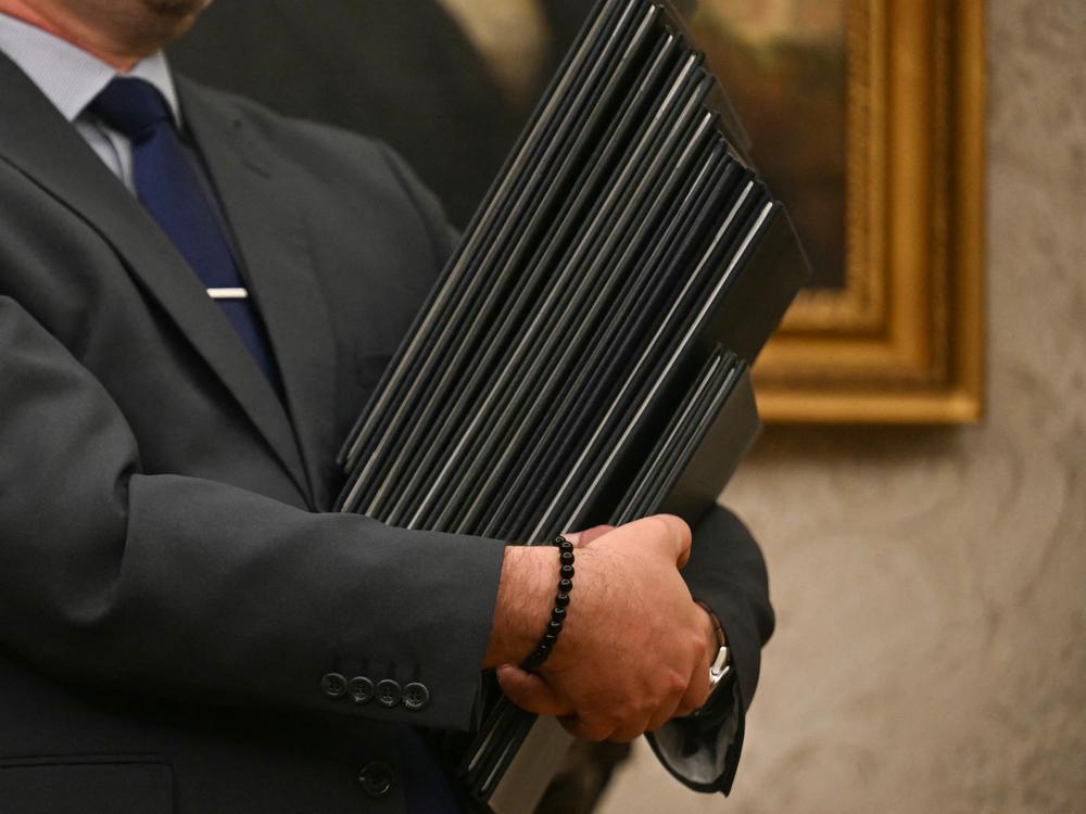 An aide holds executive orders to be signed by President Trump at the White House on Monday.