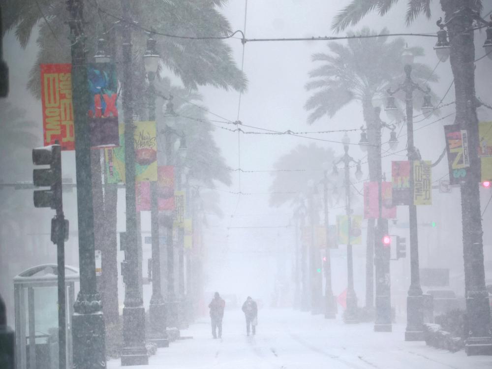 People make their way down a snowy Canal Street on Jan. 21 in New Orleans. A winter storm brought rare snowfall to the city.
