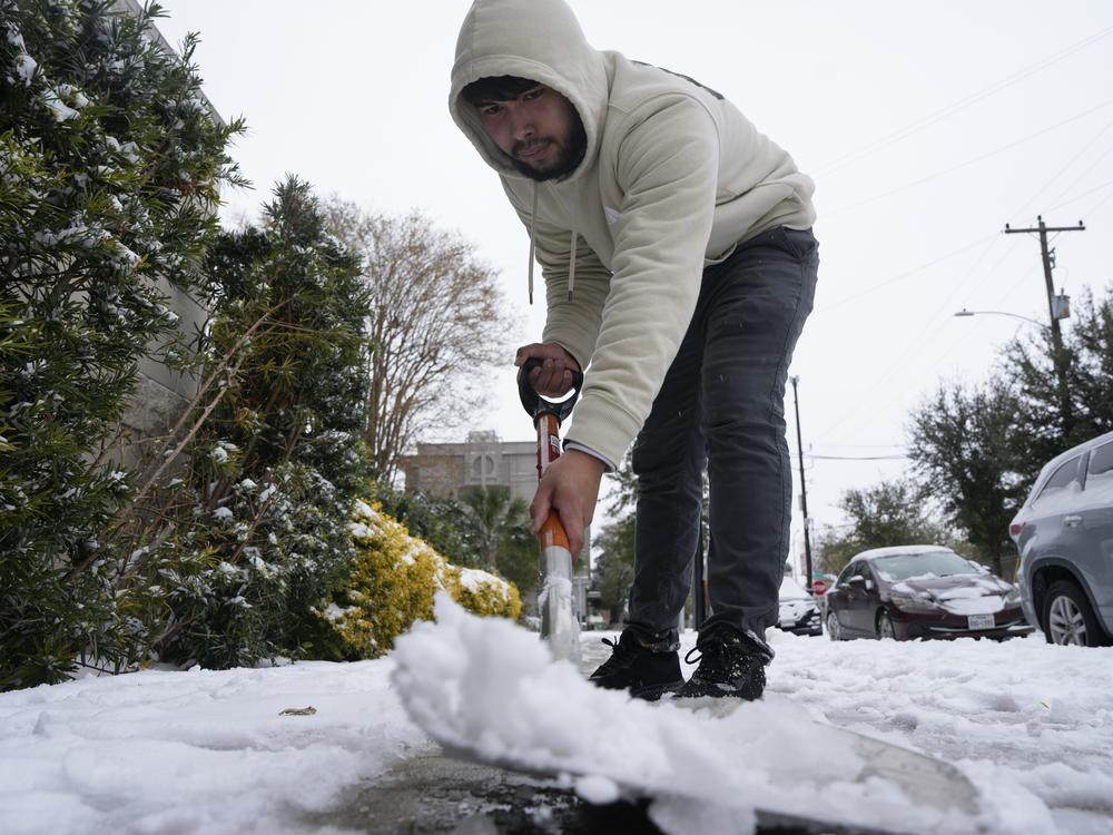 Houston, Texas: A hotel worker shovels the icy snow from the sidewalk on Jan. 21.