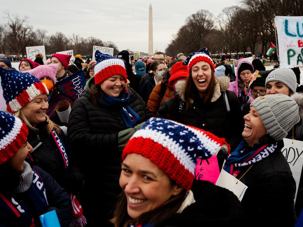 Lauren Perry, 40, third from left, and Corrine Rhodes, 40, share a laugh with their friends, all of Havertown, Pa., as thousands gather to protest Donald Trump's inauguration as the 47th president of the United States and other related issues during the People's March on Jan. 18, at the Lincoln Memorial in Washington D.C.
