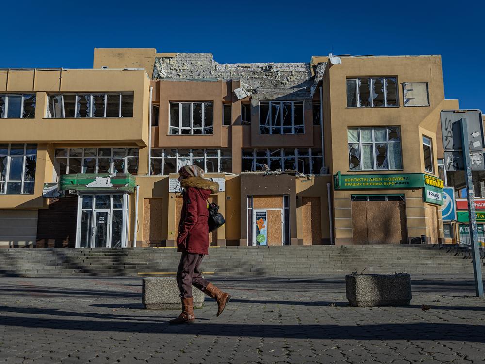 A woman walks in front of a war-ravaged shopping complex in Kherson, Ukraine, on Jan. 4. People in the city say cloudless days are most dangerous because Russian drones take advantage of the high visibility to swarm over the front-line city.