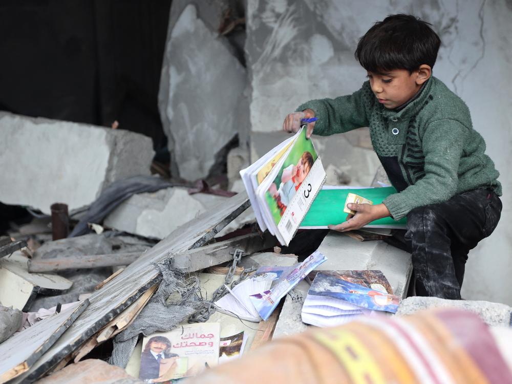 On Jan. 16, following a truce announcement amid the war between Israel and Hamas, a child recovers books from the rubble of a building hit in Israeli strikes the previous night in Jabalia, in the northern Gaza Strip.
