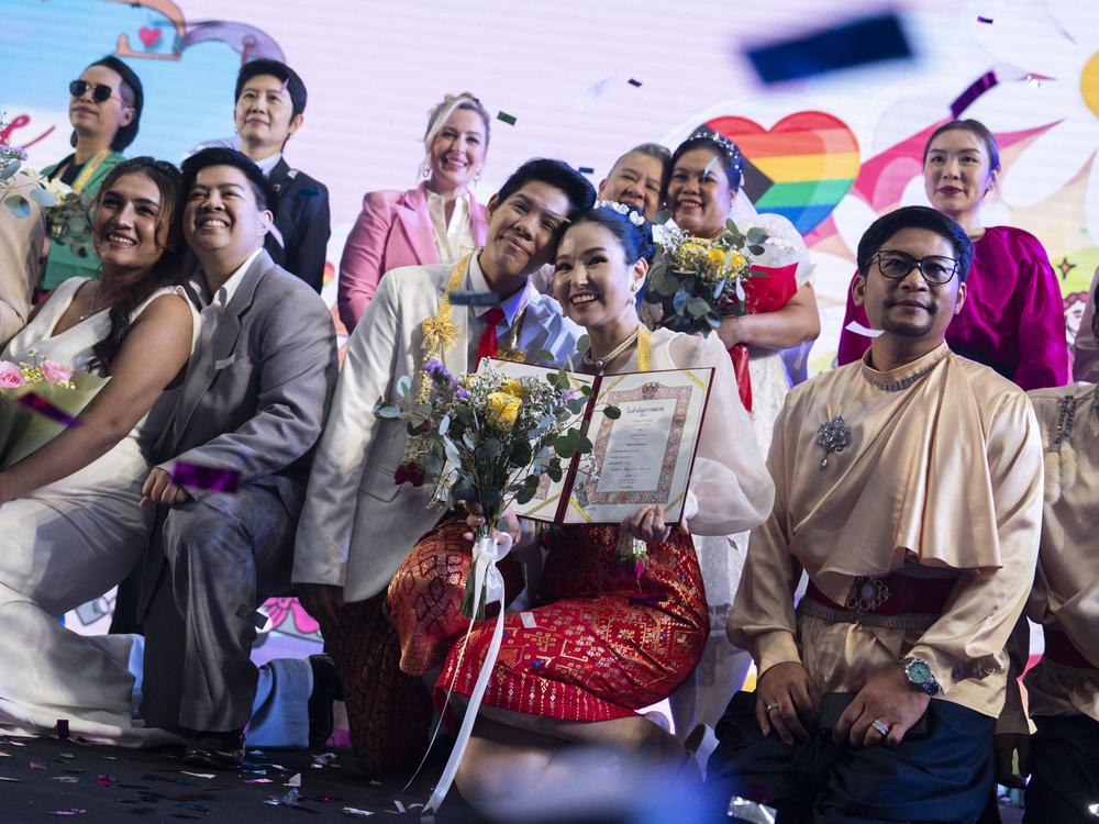 Same-sex couples pose for pictures at a marriage registration event at Paragon shopping mall in Bangkok, on Thursday.