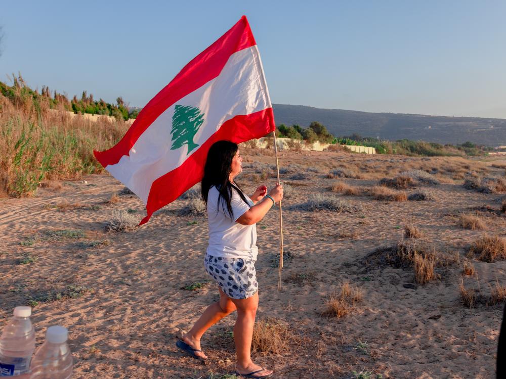Fadia Joumaa carries Lebanon's national flag as she leads a group of volunteers trying to protect sea turtles on Mansouri Beach.