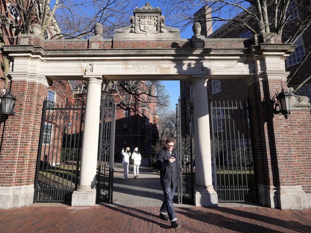 A passerby walks through a gate to the Harvard University campus, Tuesday, Jan. 2, 2024, in Cambridge, Mass.