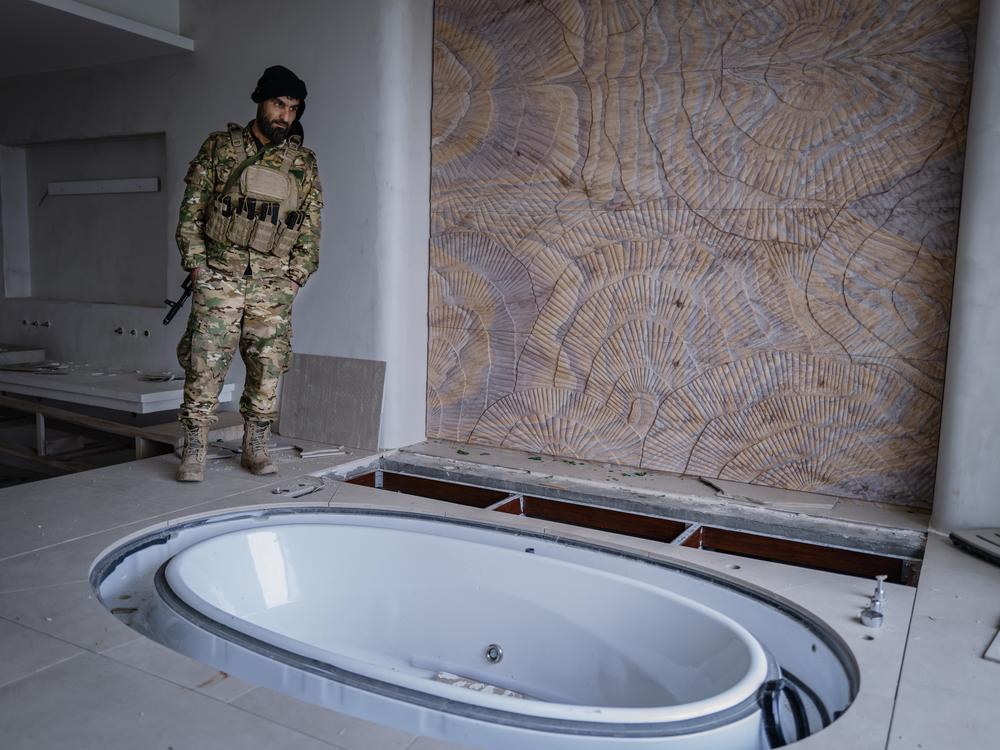 An HTS fighter stands beside the hot tub of former Syrian President Bashar al-Assad in the Assad family villa outside Latakia.