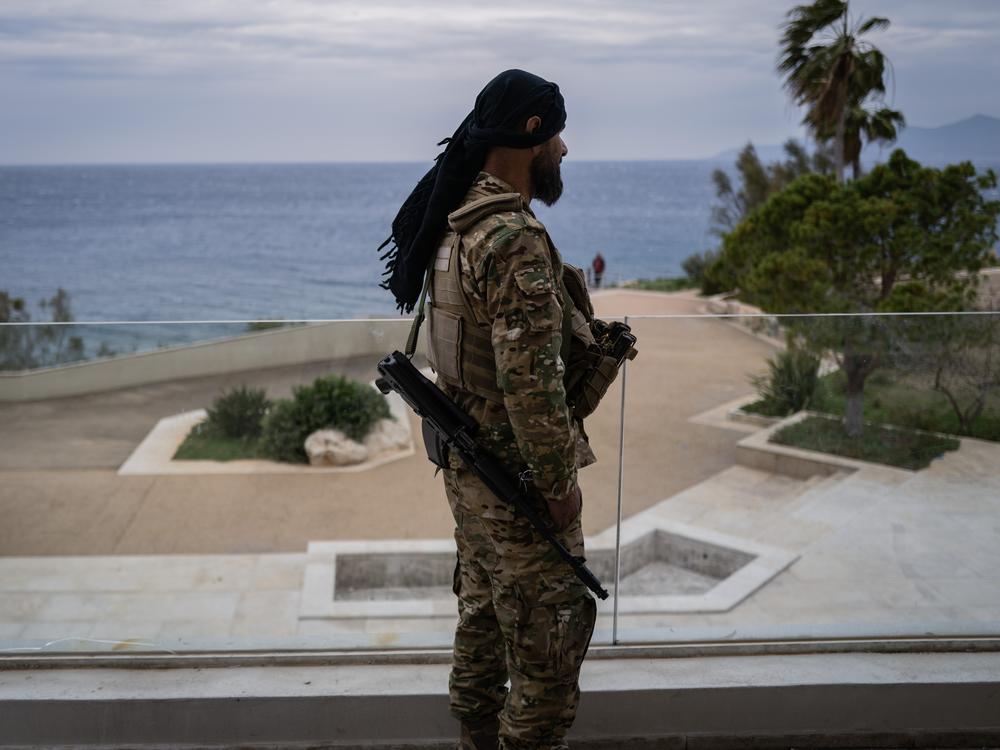 A fighter with Hayat Tahrir al-Sham, the group that led the overthrow of the Assad regime, stands on the terrace of former Syrian President Bashar al-Assad's family villa outside Latakia. After the Assad regime fell last month, the family's properties were left abandoned. One of those was the Assad summer home, with a private beach on the Mediterranean.