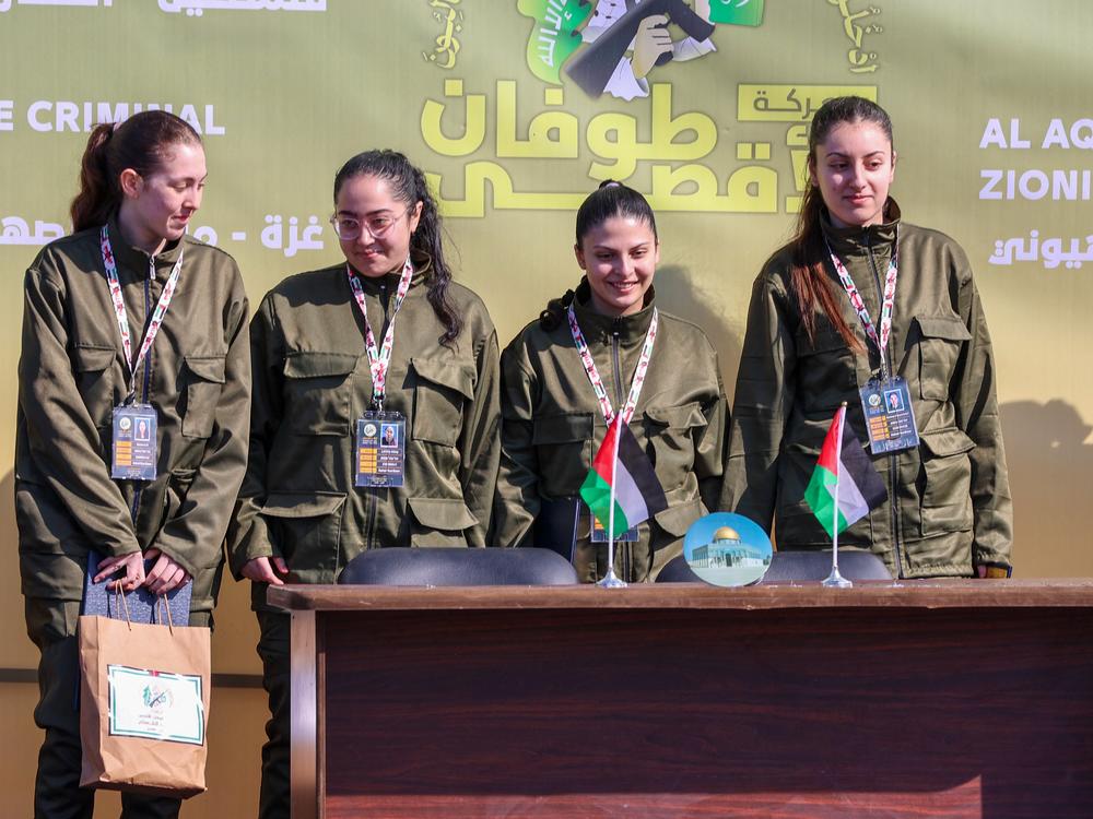 Four Israeli hostages stand on a stage before Hamas fighters hand them over to a team from the Red Cross in Gaza City on Saturday.