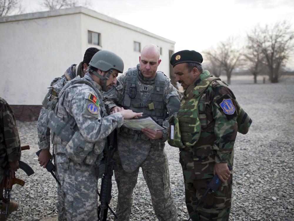 A U.S. Air Force captain goes over the day's mission route map with an Afghan National Army officer with assistance from an Afghan interpreter (left), before the U.S.-Afghan convoy sets off in Ghazni, Afghanistan, on March 16, 2009.