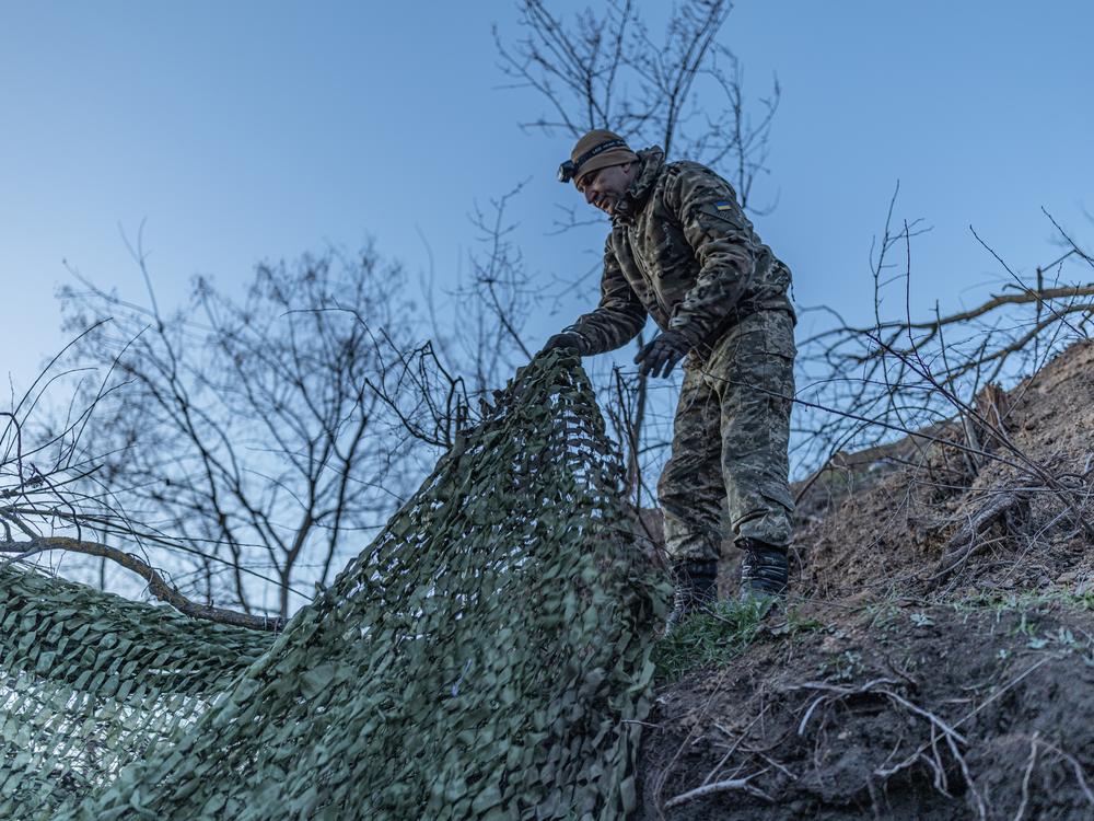 A gunner named Yurii, whose call sign is Psycho, removes a camouflage net from the BMP-1 infantry fighting vehicle.