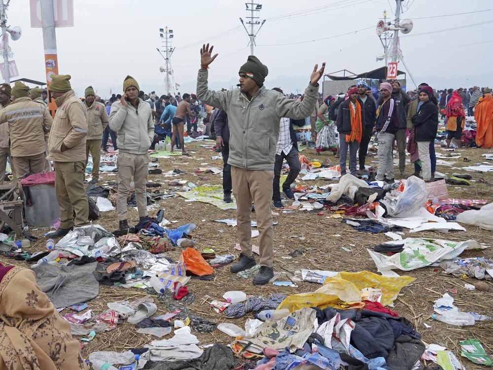 A policeman gestures as the belongings of Hindu devotees lie scattered after a stampede when Hindu devotees rushed to take a holy bath in the Sangam, the confluence of the Ganges, the Yamuna and the mythical Saraswati rivers, on 