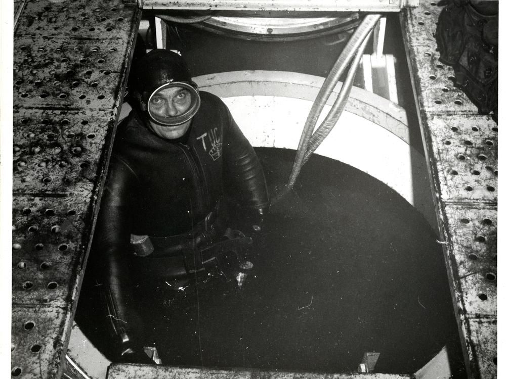 Aquanaut Cyril Tuckfield stands in an open hatch inside the Sealab II habitat.
