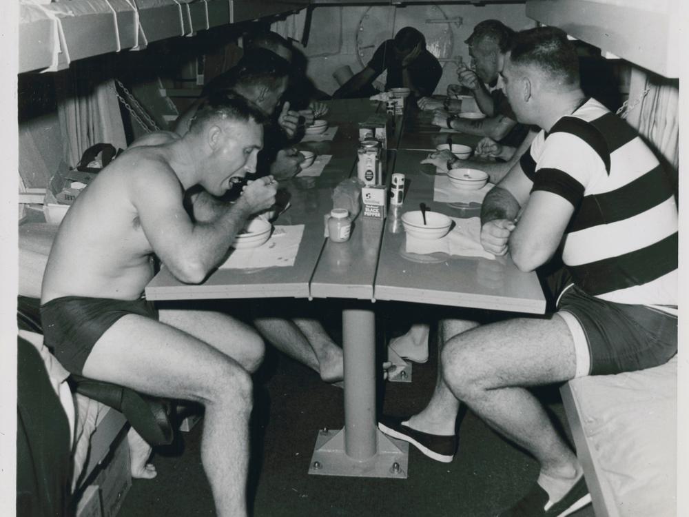 Aquanauts eat a meal inside the Sealab II habitat.