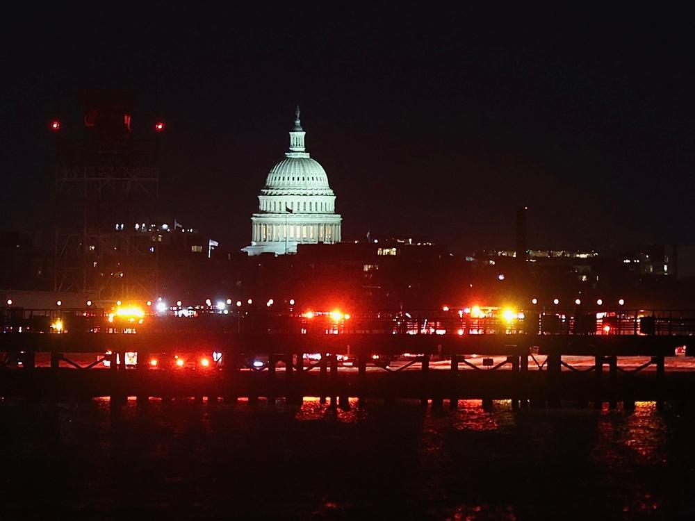 Emergency vehicles stage at Ronald Reagan Washington National Airport on Wednesday night. The U.S. Capitol is seen across the Potomac River in Washington, D.C.