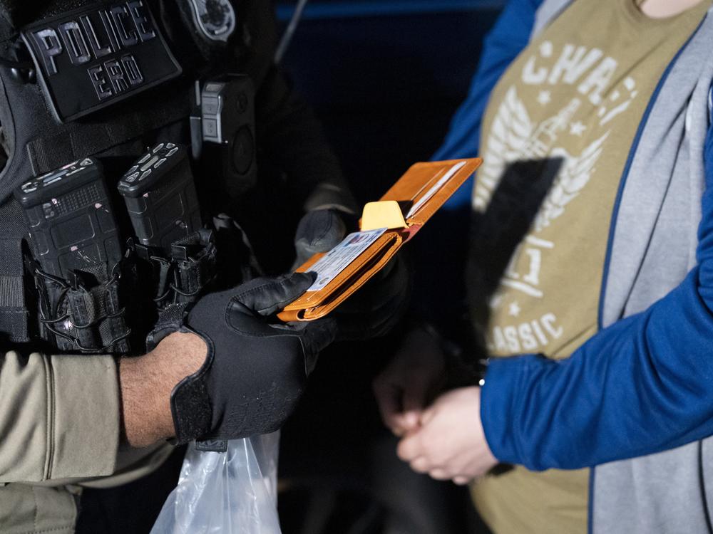 U.S. Immigration and Customs Enforcement officers look at the identification of a person detained on Monday.