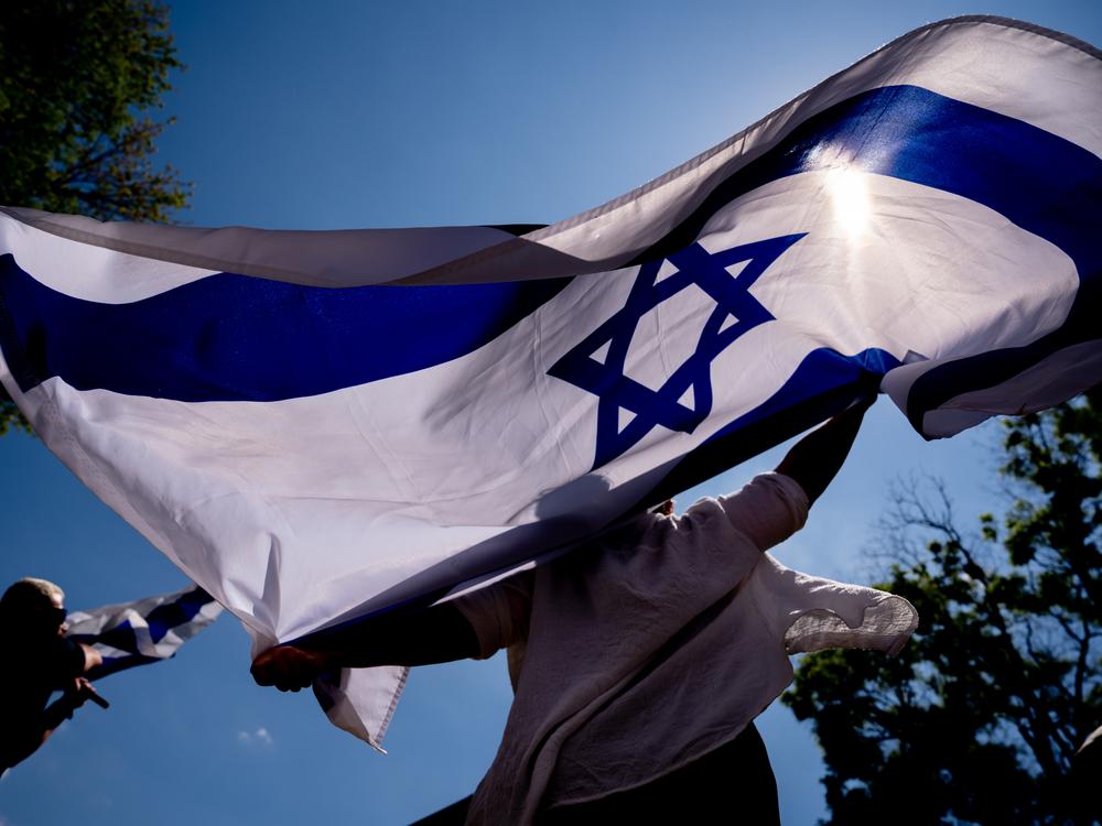 People dance and wave large Israeli flags during a rally against campus antisemitism at George Washington University in May 2024 in Washington, D.C.