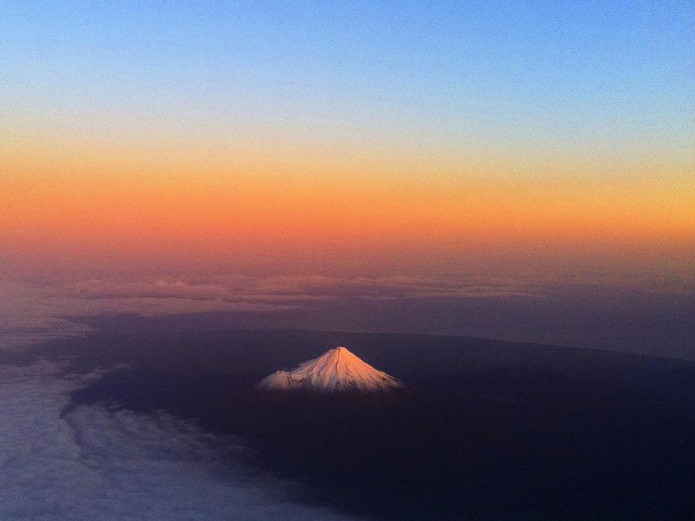 New Zealand's Mount Taranaki, also known as Mount Egmont, has a warm glow lighting the snow peak.
