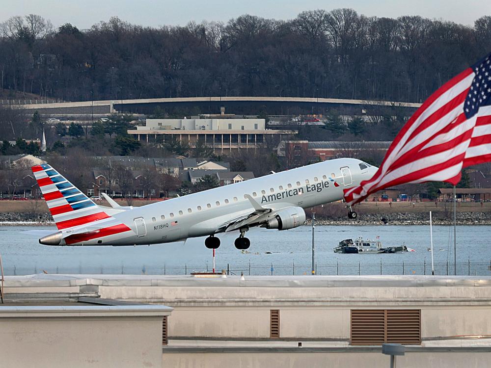 An American Airlines aircraft takes off from Ronald Reagan Washington National Airport as emergency workers continue to search the wreckage of the aircrafts that crashed into the Potomac River Wednesday night. An American Airlines flight from Wichita, Kansas collided midair with a military Black Hawk helicopter while on approach to DCA airport.