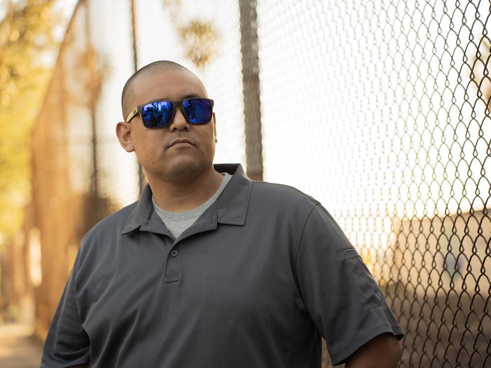 Jason Trapp, an instructional coach and former history teacher at Octavia E. Butler Magnet, stands outside the fence of his school on Jan. 15. His family lost their home to the Eaton fire.