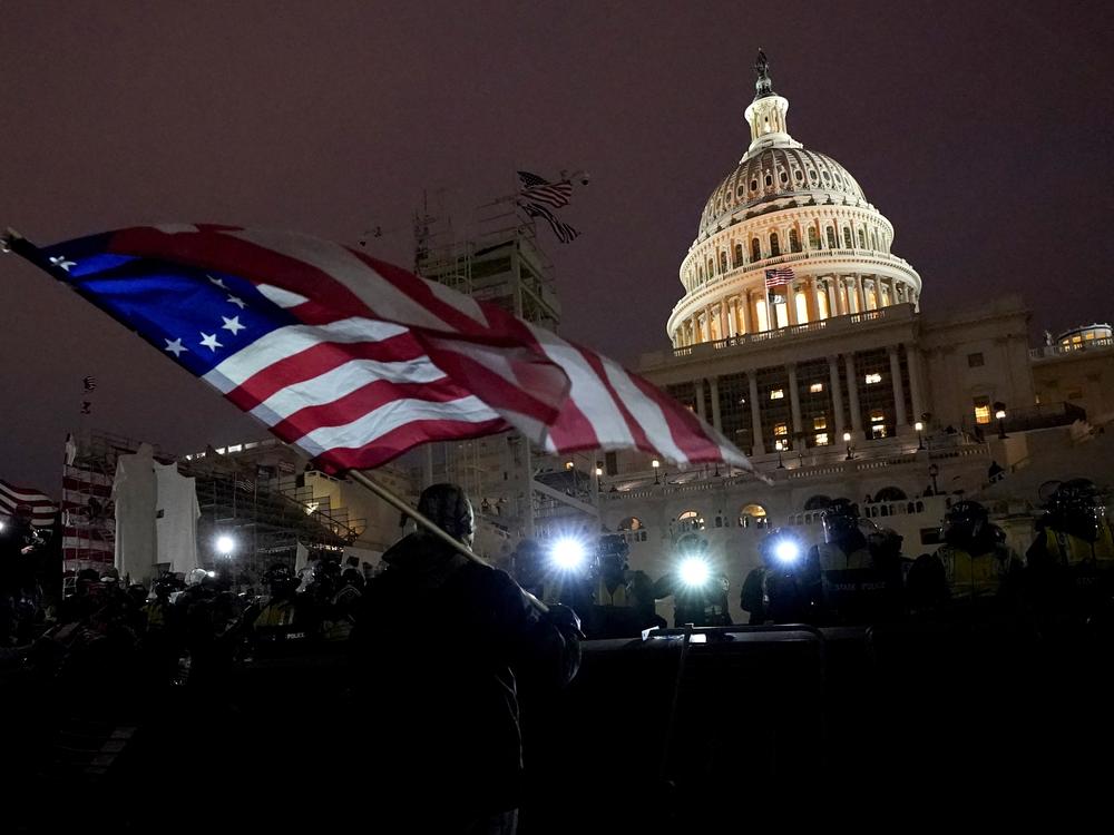 Protesters hold flags as they are pushed back by police on Jan. 6, 2021, after President Trump's supporters stormed the U.S. Capitol. Trump pardoned almost every person who participated in the riot.