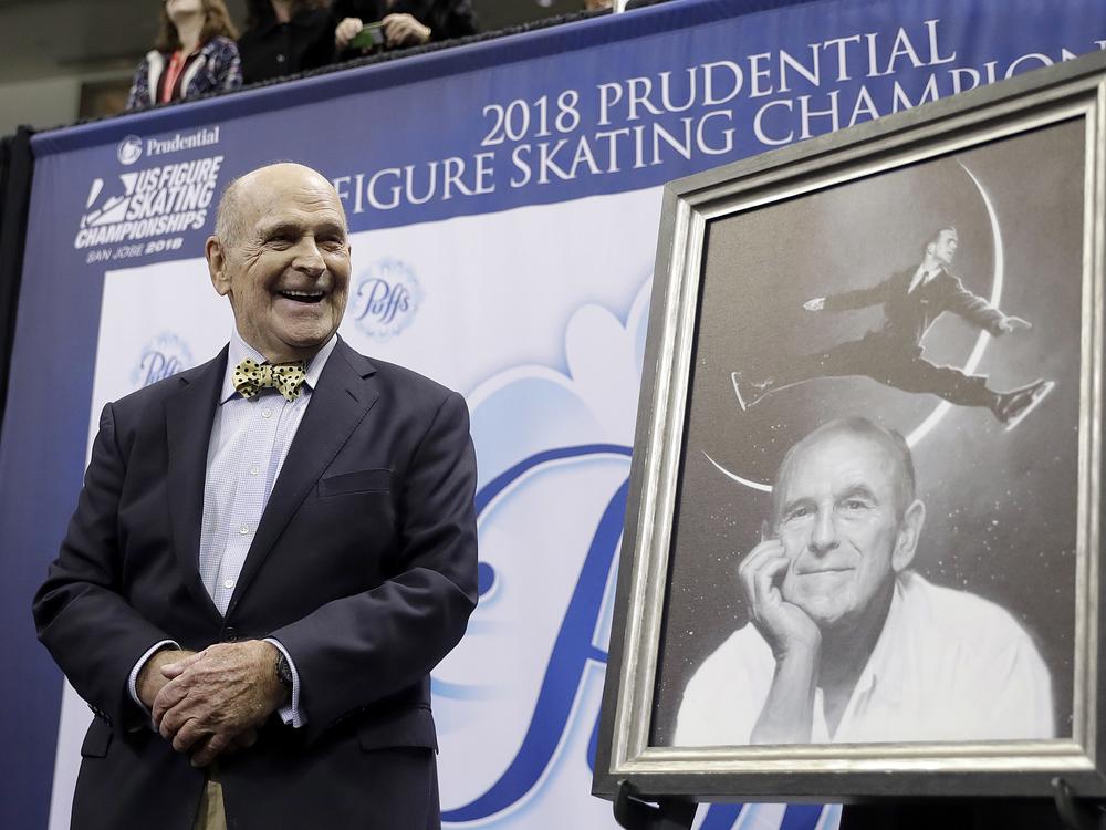 Dick Button smiles next to a painting of him while honored at the U.S. Figure Skating Championships in San Jose, Calif., Thursday, Jan. 4, 2018.