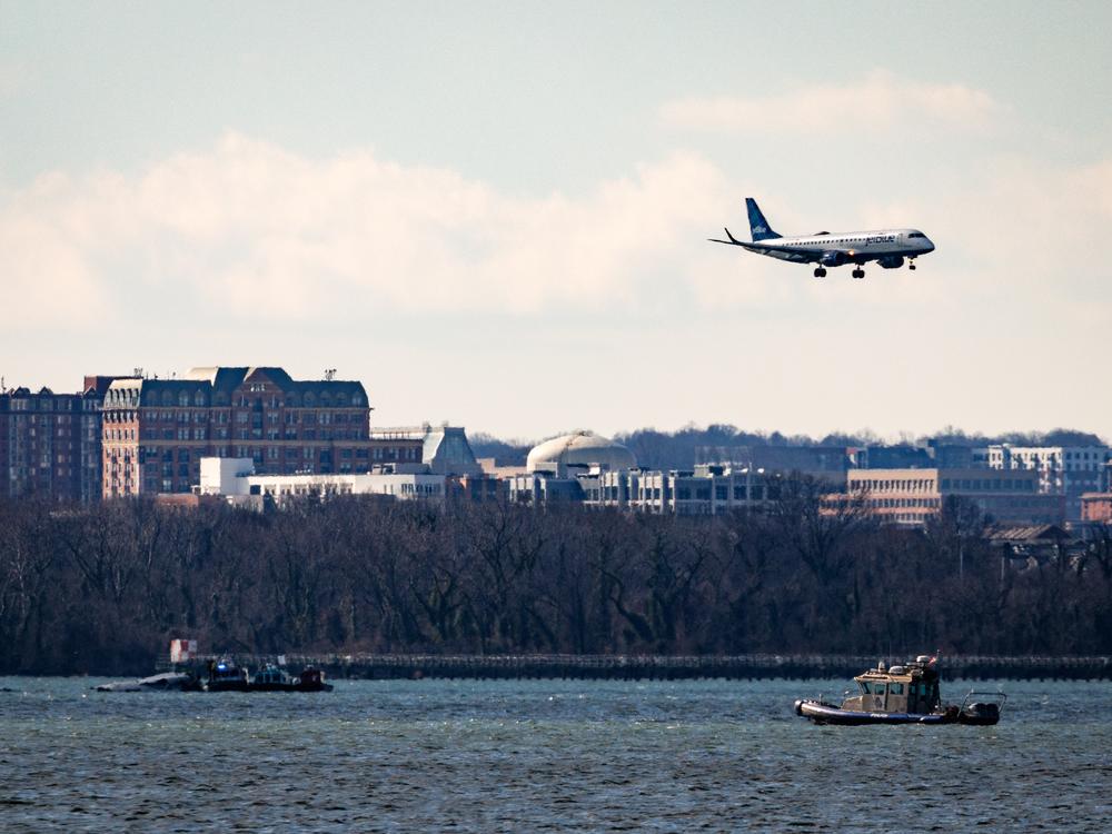 A flight flies over law enforcement boats and the partially submerged fuselage of American Airlines Flight 5342 in the Potomac River on Saturday in Washington, D.C.