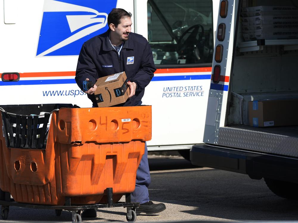 A U.S. Postal Service employee is shown loading parcels outside a post office in Wheeling, Ill., on Jan. 29, 2024.