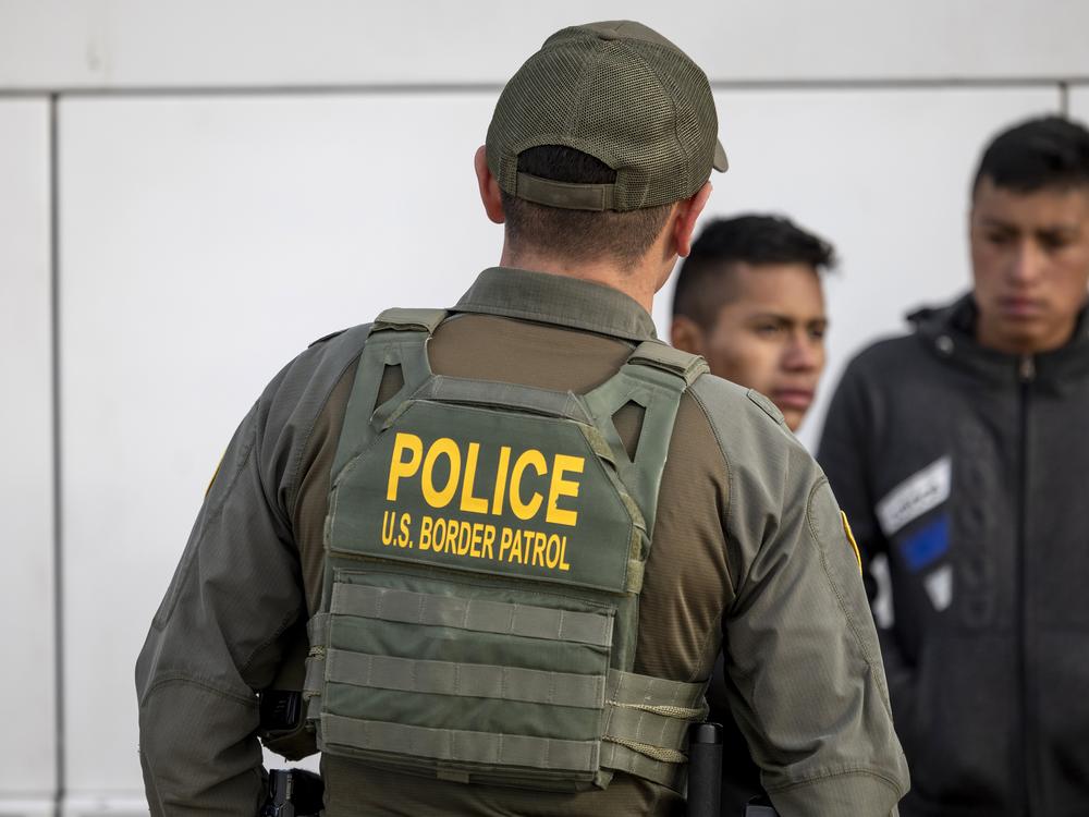 A U.S. Border Patrol agent watches as immigrants prepare to board a bus after crossing the U.S.-Mexico border on Jan. 7, 2024 in Eagle Pass, Texas.