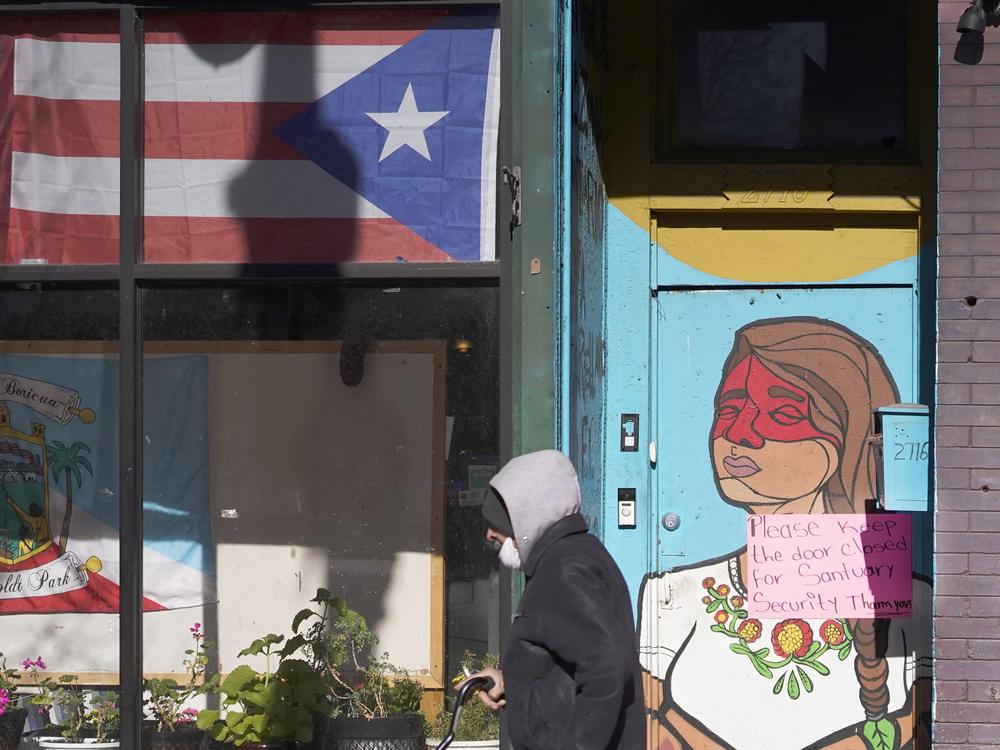 A pedestrian walks past the flag of Puerto Rico and the colorful door to the sanctuary apartment of Chicago's Adalberto Memorial United Methodist Church in Chicago in 2021. The church has provided shelter to immigrants in the U.S. illegally.