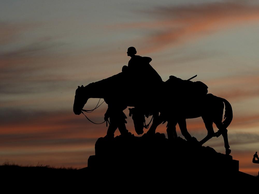 A man takes a photo as he visits the Pioneer Mother Memorial as the sun sets Thursday, March 19, 2020, in Kansas City, Mo.