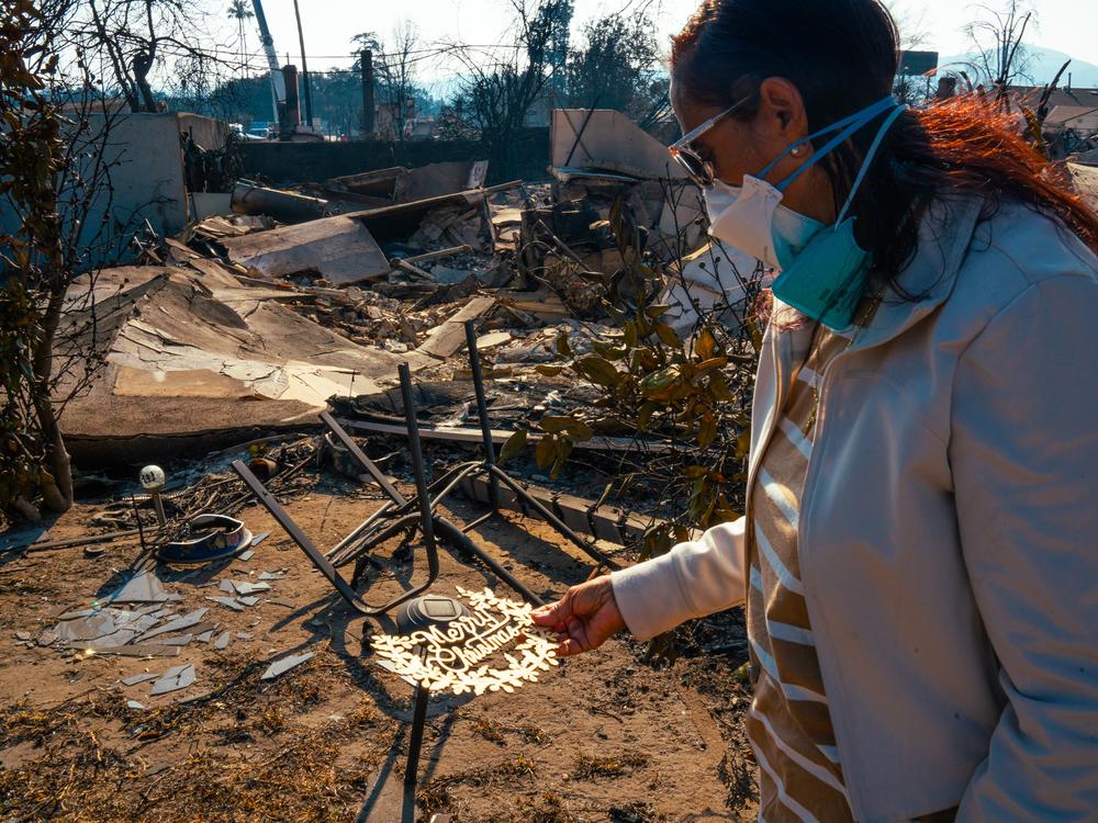 Margaret Larkin holds a piece of her Christmas decor outside of what remains of her home. Larkin lived on her block in Altadena, Calif. for 36 years.