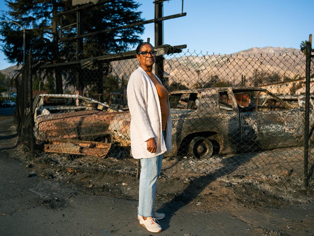 Veronica Jones, the Altadena Historical Society's first Black president, stands in front of a lot full of burned cars on Jan. 21, 2025. The Eaton Fire came just a block away from her home in west Altadena.