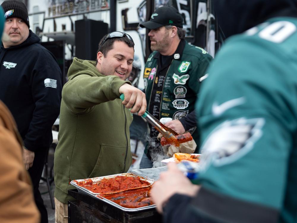 Anthony Byrne serves sausage sandwiches at his uncle Ed Callahan's (not pictured) tailgate. The food and drinks are free. In lieu of payment, Callahan asks participants to donate to the raffle which benefits the Eagles Autism Foundation.