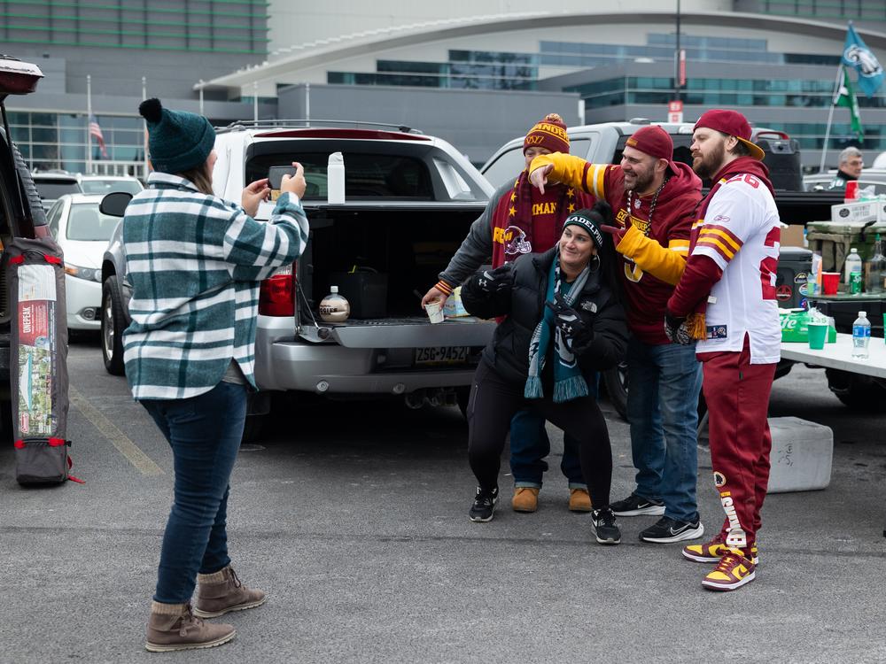 Eagles fans can be tough on the fans of visiting teams. But Washington Commanders fans Eddie Jenkins (right) and Kenny Alvo (second to right) were warmly welcomed at a tailgate before the NFC championship game in Philadelphia.