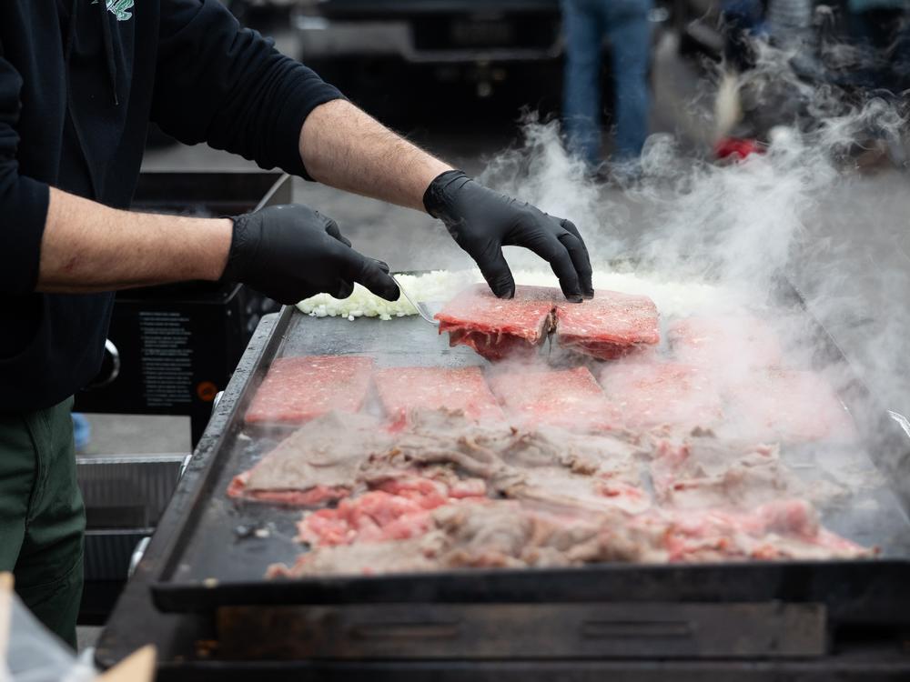 Chris Tsoubis, owner of Old English Pizza, prepares free cheesesteaks at the tailgate of Ed Callahan (not pictured). Callahan estimates the tailgate serves thirty to forty pounds of cheesesteaks before the game.