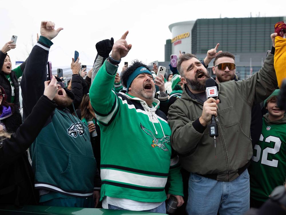 Former Philadelphia Eagles center Jason Kelce (right) leads fans in a cheer during a TV segment in the parking lot of Lincoln Financial Field.