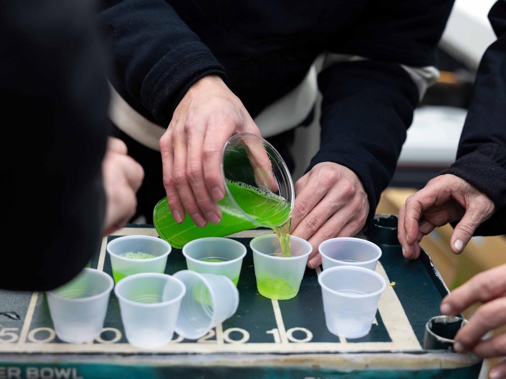 Tailgaters prepare free shots at Ed Callahan's (not pictured) tailgate in the parking lot of Lincoln Financial Field.