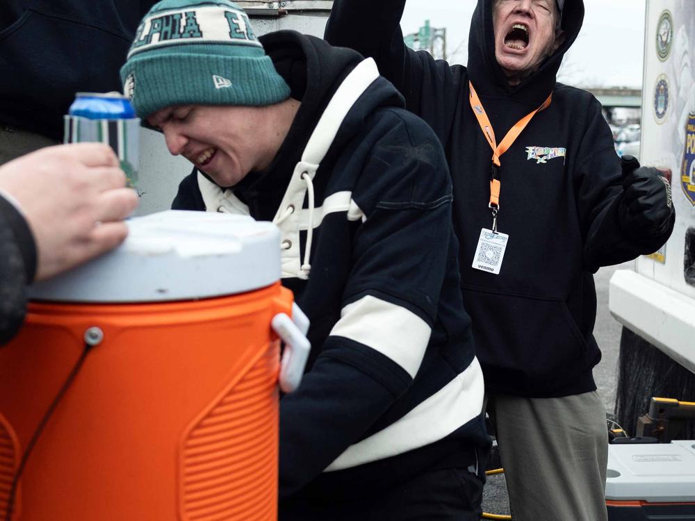 Ed Callahan (right) yells an E-A-G-L-E-S cheer at his tailgate before the Eagles NFC championship game against the Washington Commanders.