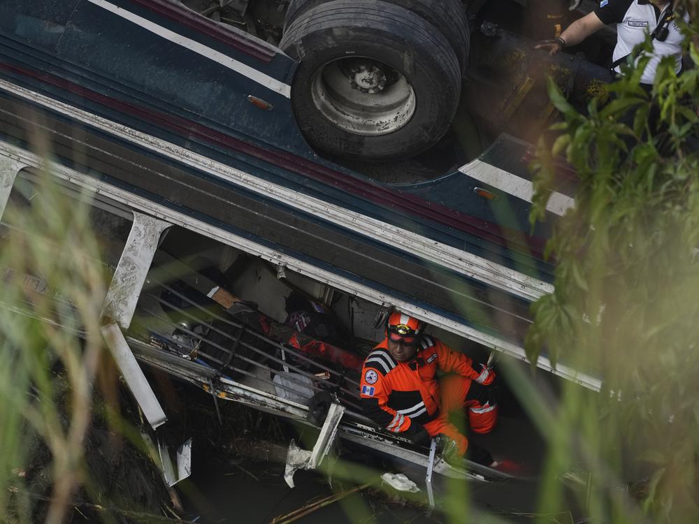 A firefighter works inside a bus that fell from a bridge, at the site of the fatal bus crash on the outskirts of Guatemala City, Monday, Feb. 10, 2025.