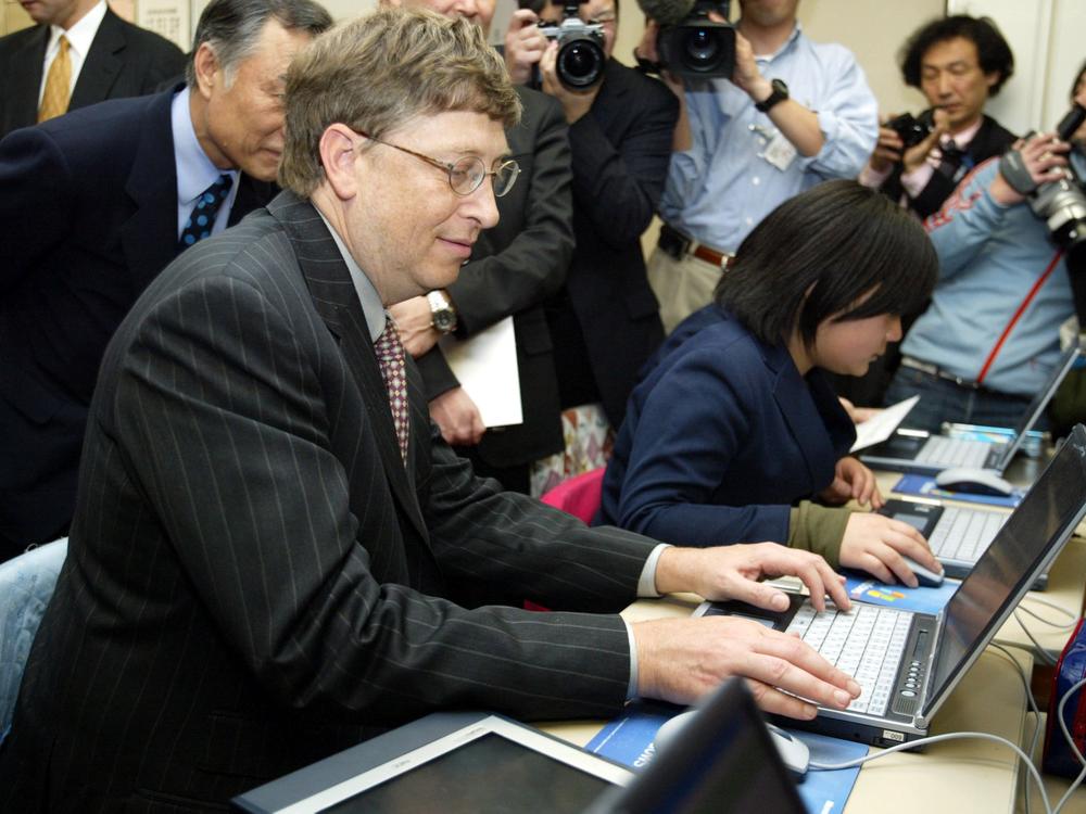 In a file photo from 2003, Bill Gates sits at a computer in a primary school in Tokyo, Japan.