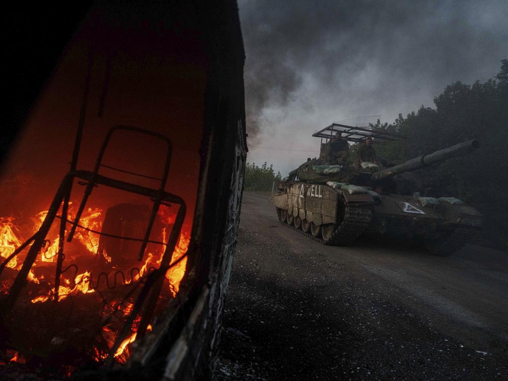A Ukrainian tank passes by a burning car near the Russian-Ukrainian border, Sumy region, Ukraine, on Aug. 14, 2024.