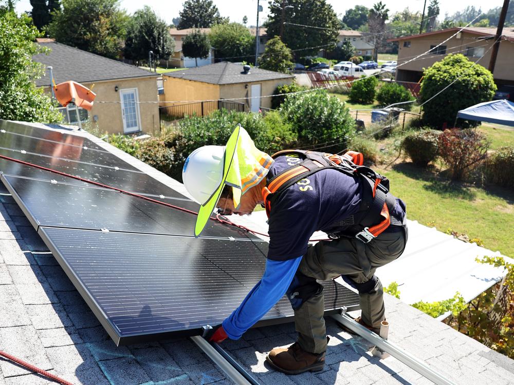 A worker installs no-cost solar panels on the roof of a low-income household in 2023 in Pomona, Calif.
