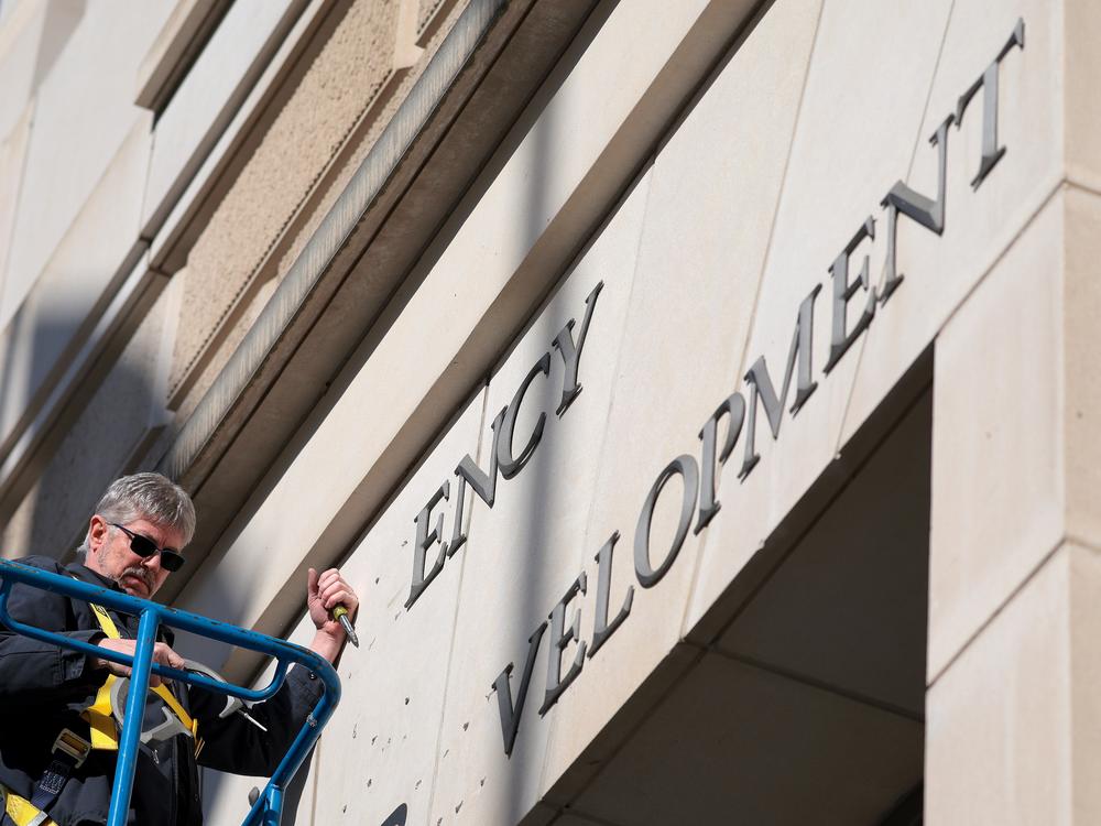A worker removes the U.S. Agency for International Development sign on their headquarters on February 7. A judge is set to extend the pause of President Donald Trump's plan to put employees on administrative leave.